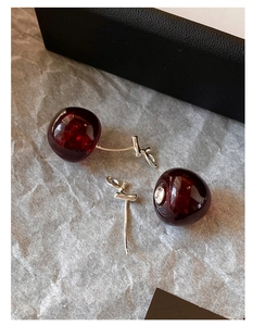 Detailed view of dark red resin cherry earrings with silver leaf and pin structure