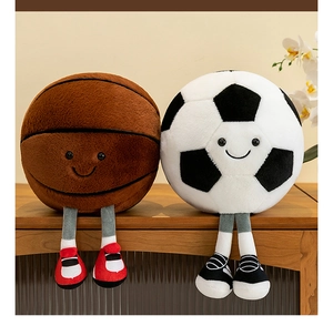 Plush basketball and soccer toys with smiling faces and dangling legs on a wooden shelf
