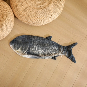 Realistic fish plush pillow shell with black scale texture on a light wood floor background