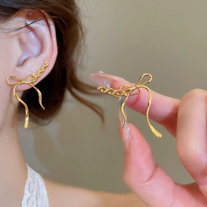 Detail of elegant gold ribbon bow earrings showing worn effect and hand-held size scale