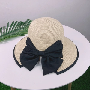Détail du grand nœud noir sur chapeau de paille beige avec bordure noire élégante