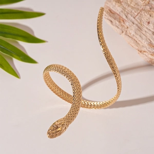 Detailed view of snake-shaped golden bracelet with textured scales on natural stone
