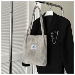 Detail of light grey corduroy tote bag with aesthetic fabric patch on black blazer
