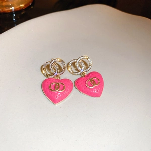 Detail of pink heart-shaped earrings with gold plating and white sparkling crystals