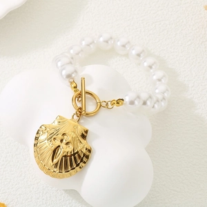 Détail macro du pendentif coquille dorée et perles sur le bracelet à fermoir OT