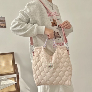 Detail of pink quilted tote bag with floral rabbit patterns and branded woven label