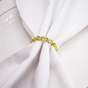 Elegant gold hollow heart napkin ring set on white cloth for dining table decor
