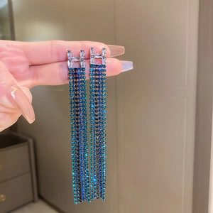 Macro detail of H-shaped rhinestone stud earrings with long blue crystal tassels