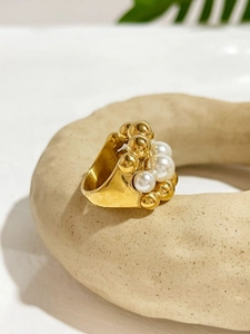 Detailed close-up of a layered gold stainless steel ring with white pearls and beads