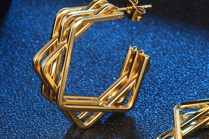 Close-up of golden geometric multi-layer square stud earrings on a dark blue background