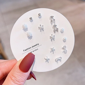Close-up of silver stud earring set with pearls, zircons and delicate bow-knot designs