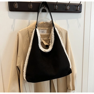 Detail of black suede tote bag featuring white faux shearling trim and stylish handle