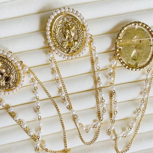 Detailed view of vintage gold coin brooches with pearls and layered dangle chains