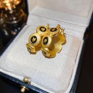 Détail de boucles d'oreilles vintage en or avec émail noir Méduse et motif méandre grec