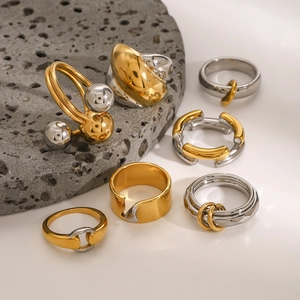 Minimalist gold and silver two-tone stainless steel rings on gray volcanic stone base