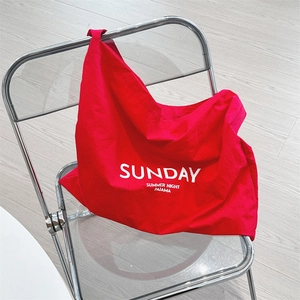 Detail of red canvas tote bag with Sunday print on transparent folding chair