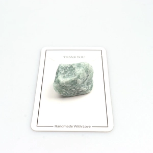Macro shot of natural raw green stone specimen on white card for crystal collection