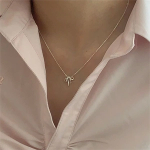 Minimalist 925 sterling silver bow pendant necklace shown on a female model