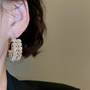Gros plan de boucles d'oreilles créoles dorées à double rangée serties de zircones