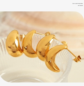 Macro shot of 18K gold plated crescent moon hoop earrings on textured glass