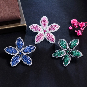 Detailed macro view of five-petal flower brooches with micro-pave crystals and colorful gems