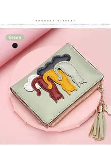 Close-up of light green short wallet featuring cat patches and leather tassel detail