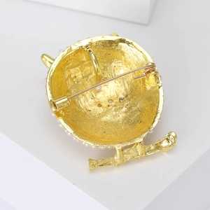 Detailed back view of a golden owl brooch with a pin clasp and elegant pearl accents