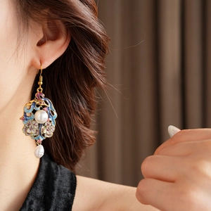 Close-up of vintage enamel floral earrings with pearls worn by a model in soft light