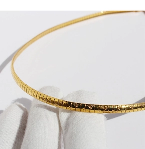 Macro shot of gold-plated flat snake bone choker showing fine metallic texture and craft