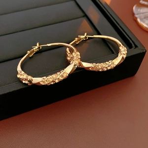 Macro shot of gold twisted hoop earrings with micro-set yellow rhinestones details