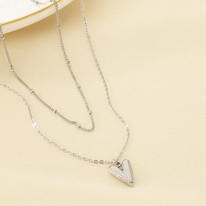 Macro shot of silver dual-layer necklace with hammered texture heart pendant on paper