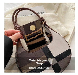 Detail einer karierten Schultertasche mit Goldschnalle auf weißem Blazer