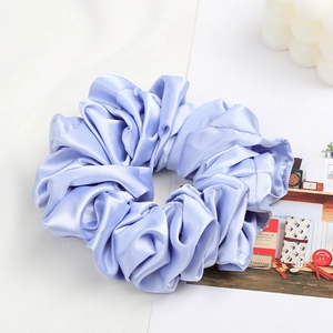Detail of light blue-purple satin scrunchie with a silky texture and pleated structure