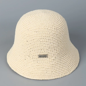 Close-up of beige hand-woven bucket hat with detailed crochet pattern and metal label