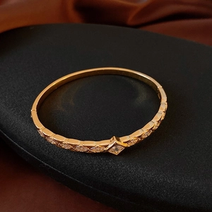 Détail macro d'un bracelet vintage doré avec zircon losange et motif de grille texturé
