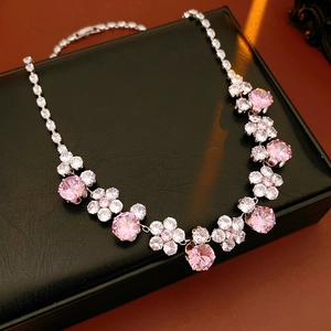 Macro view of pink and white zircon flower necklace on a luxury black leather texture box