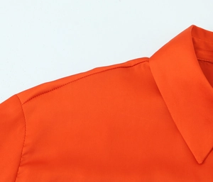 Detail of orange satin shirt collar and shoulder seam with premium stitching finish