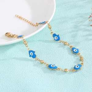 Detail of Hamsa Hand and Evil Eye enamel charms on a gold-plated beaded bracelet