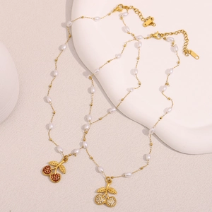 Elegant 18K gold plated stainless steel cherry necklaces with white pearls on a ceramic dish