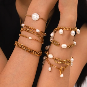 Layered gold chain bracelets with natural freshwater pearls on a woman's wrist