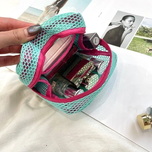 Close-up of mesh makeup bag in turquoise and pink showing storage capacity for cosmetics