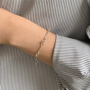 Detail of S925 sterling silver thin bracelet featuring irregular twisted knot design on wrist