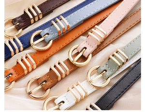 Flat lay of colorful PU leather belts with gold round buckles on beige silk fabric