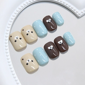 Kawaii brown bear and blue polka dot press-on nails set on a decorative white tray