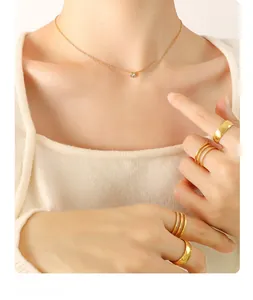 Detail of elegant 18K gold-plated necklace with zircon and stackable gold rings on a model