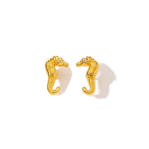 Macro detail of golden seahorse earrings featuring textured texture and white zircon stone