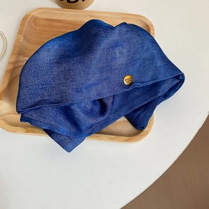 Macro view of blue denim fabric beret with gold metal buckle and believe engraving
