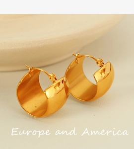 Close-up of golden wide C-shaped hoop earrings with a polished metallic finish