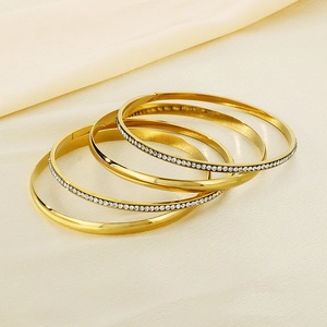 Detail of 4-piece stackable gold bangles with smooth finish and rhinestone settings