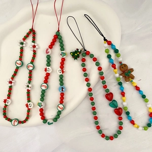 Christmas beaded phone charms featuring gingerbread man and tree icons on white fabric